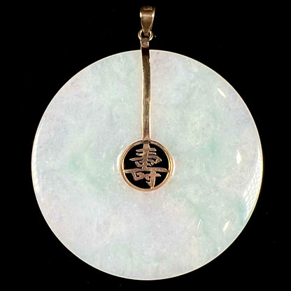 A light green jadeite jade bi pendant with a yellow gold bail and Chinese character symbol for "long life."