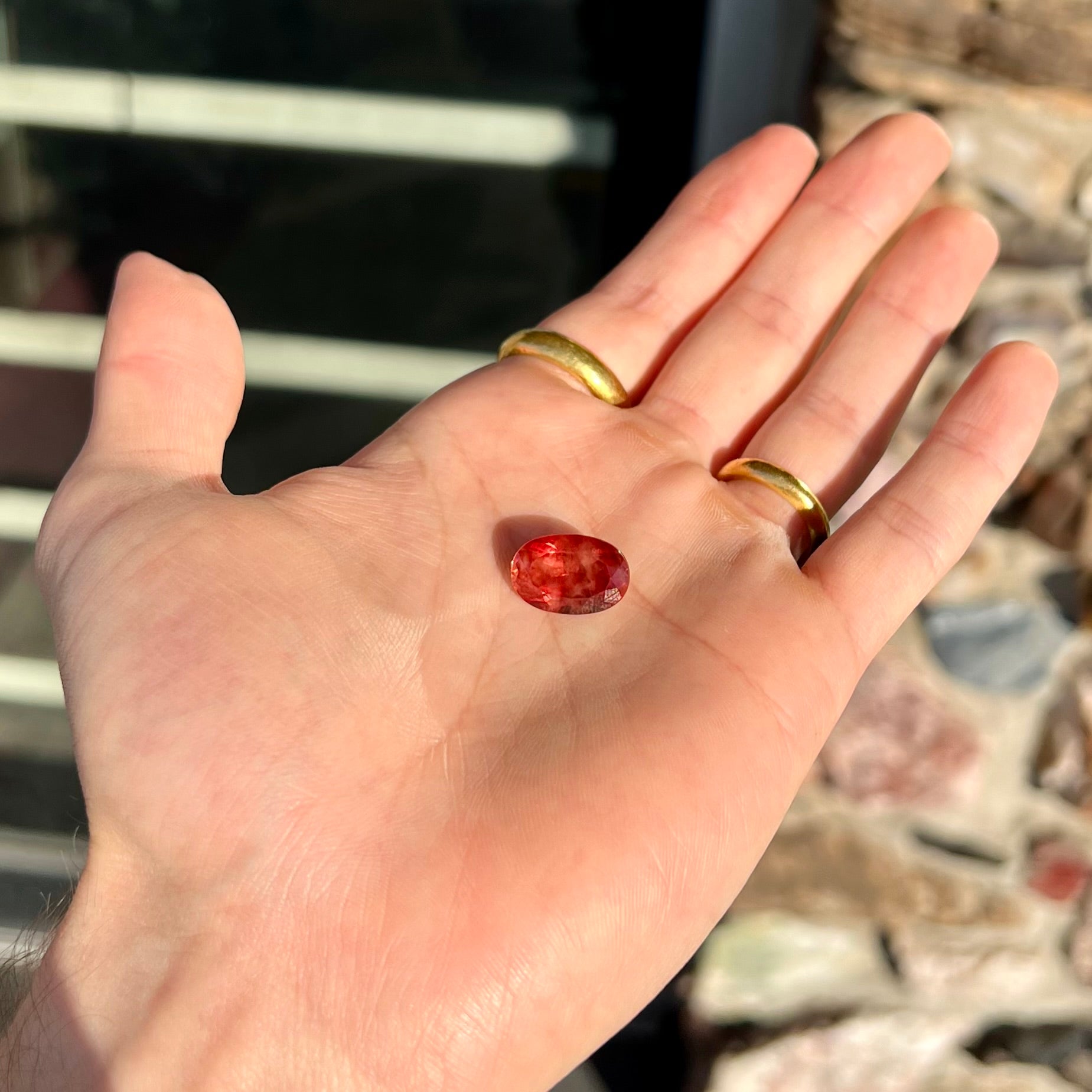 A faceted, oval cut sunstone.  The stone is red-orange color with a bright schiller flash.