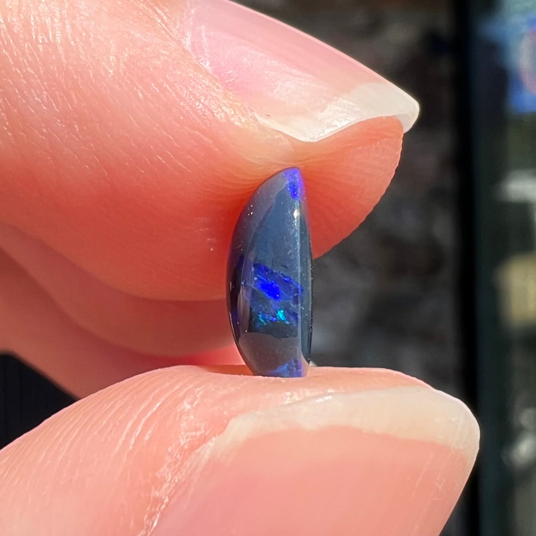A loose, oval cabochon cut black opal stone from Lightning Ridge, Australia.  The opal has an N2 body tone.