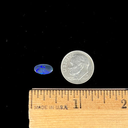 A loose, oval cabochon cut black opal stone from Lightning Ridge, Australia.  The opal has blue color play.