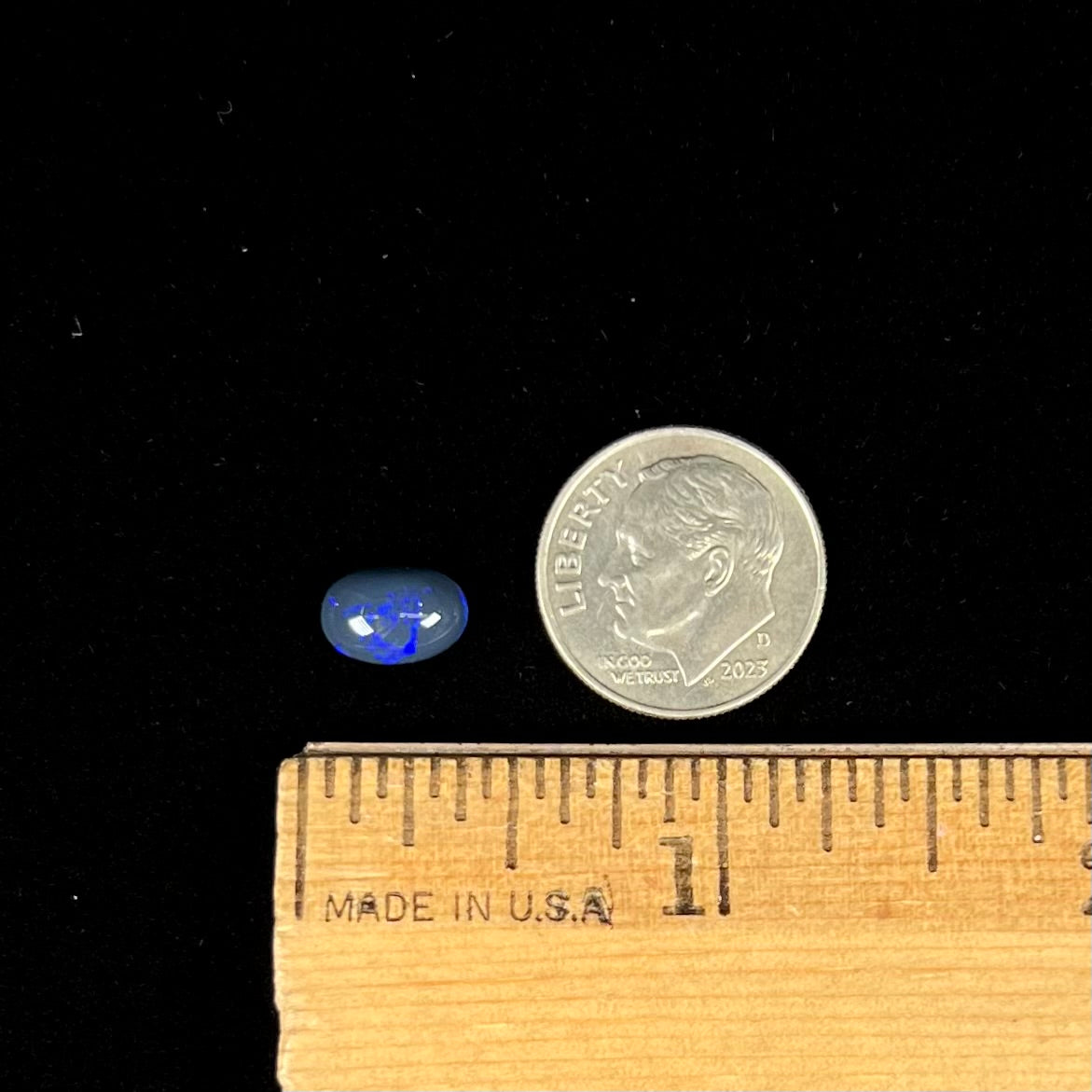 A loose, oval cabochon cut black opal stone from Lightning Ridge, Australia.  The opal has an N2 body tone.