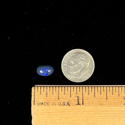 A loose, oval cabochon cut black opal stone from Lightning Ridge, Australia.  The opal has an N2 body tone.