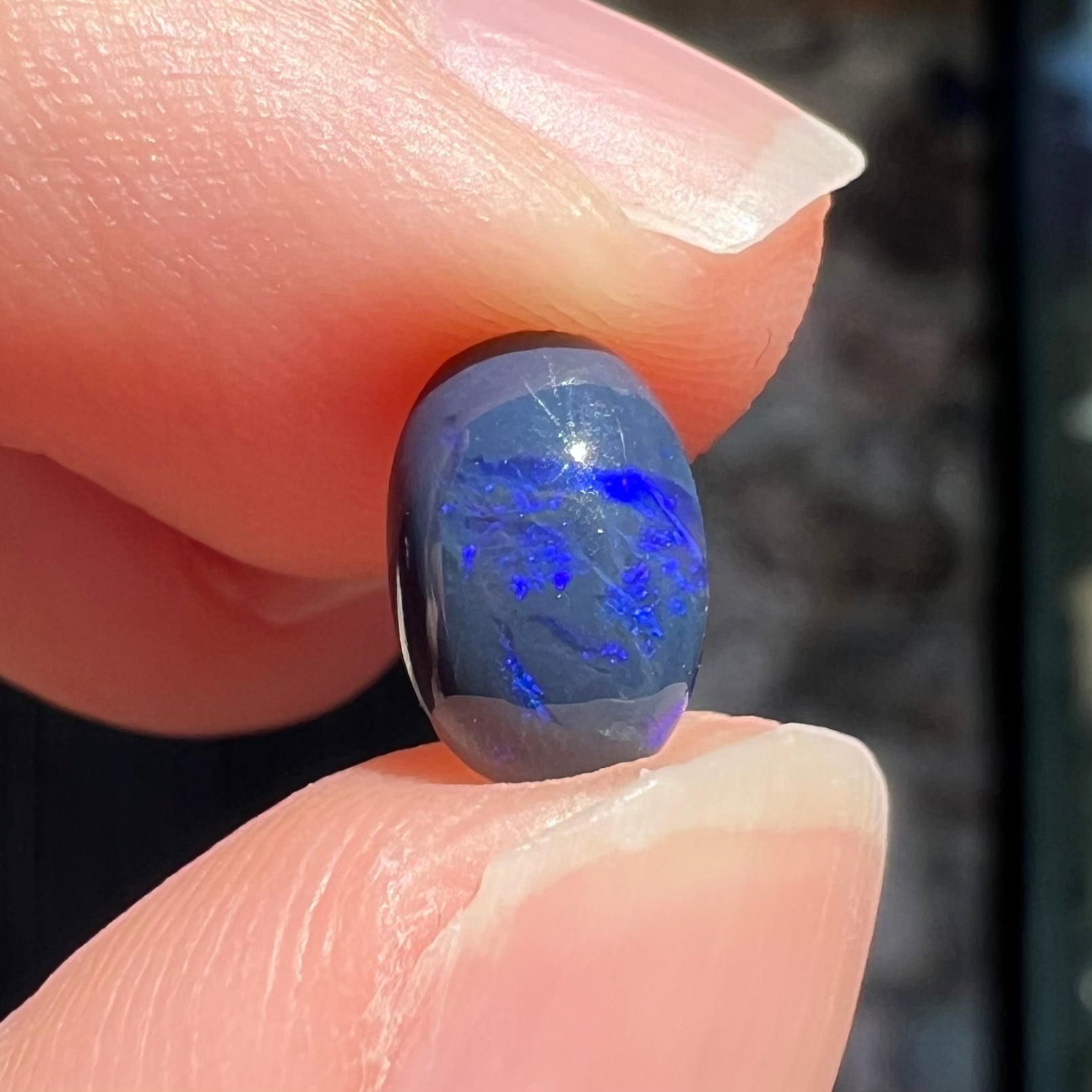 A loose, oval cabochon cut black opal stone from Lightning Ridge, Australia.  The opal has an N2 body tone.