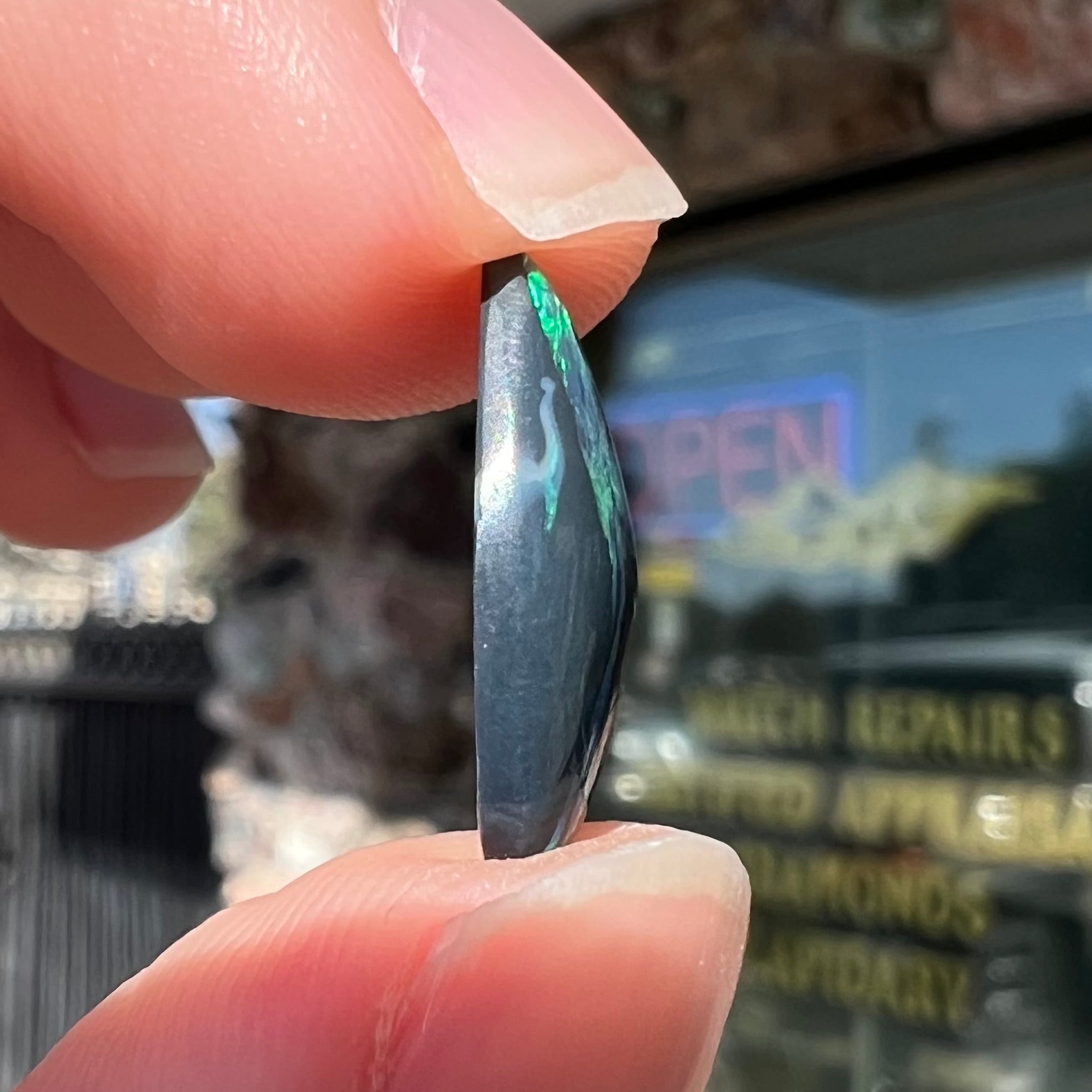A freeform pear shaped black opal from Lightning Ridge, Australia.