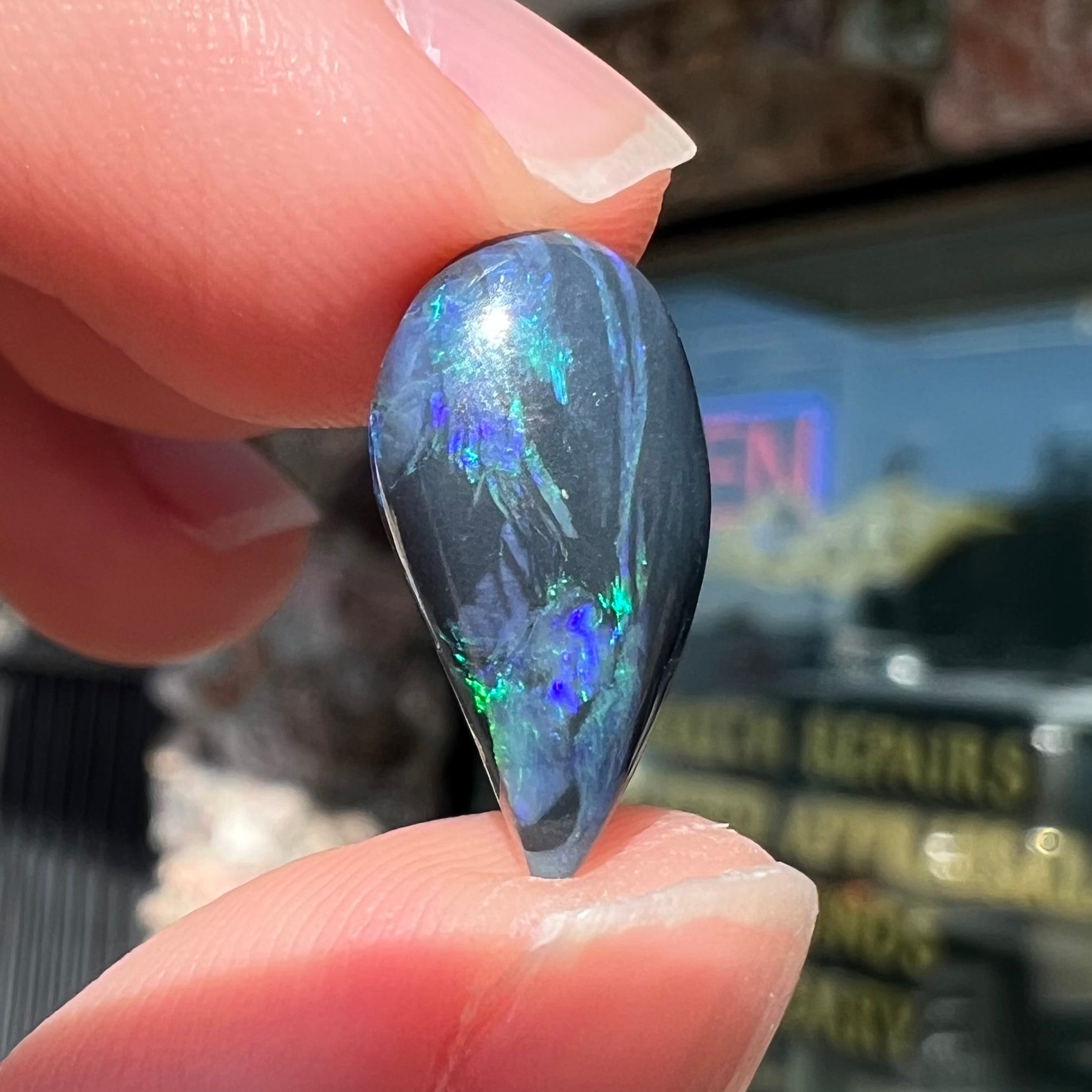A freeform pear shaped black opal from Lightning Ridge, Australia.