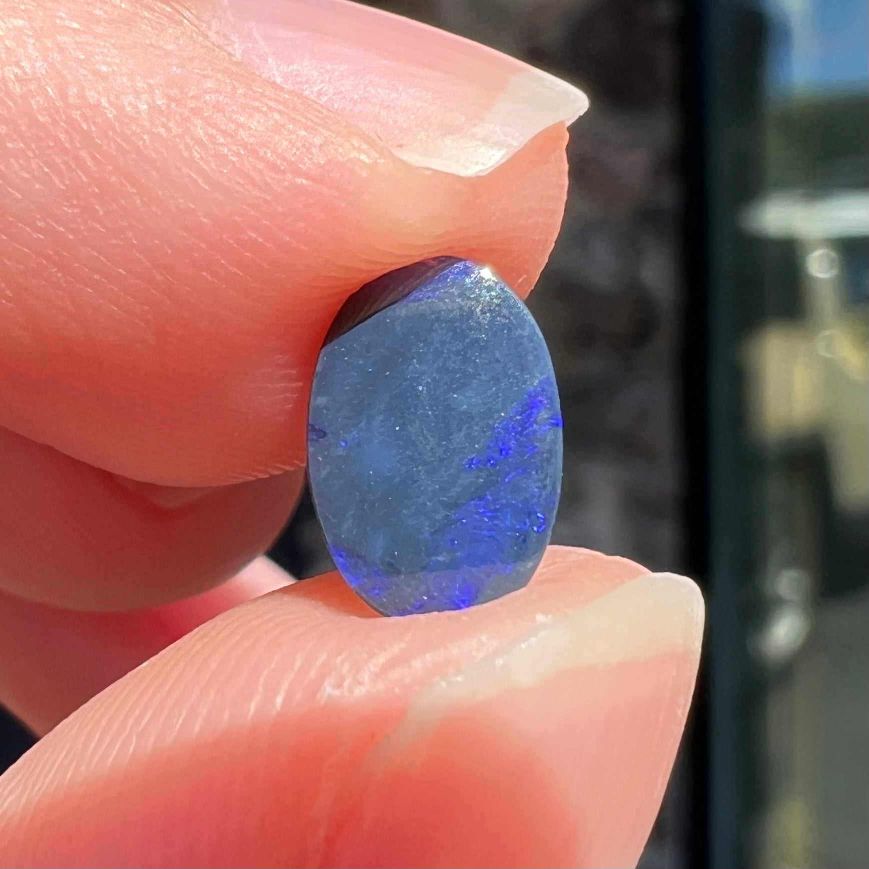 A loose, oval cabochon cut black opal stone from Lightning Ridge, Australia.  The opal has an N2 body tone.