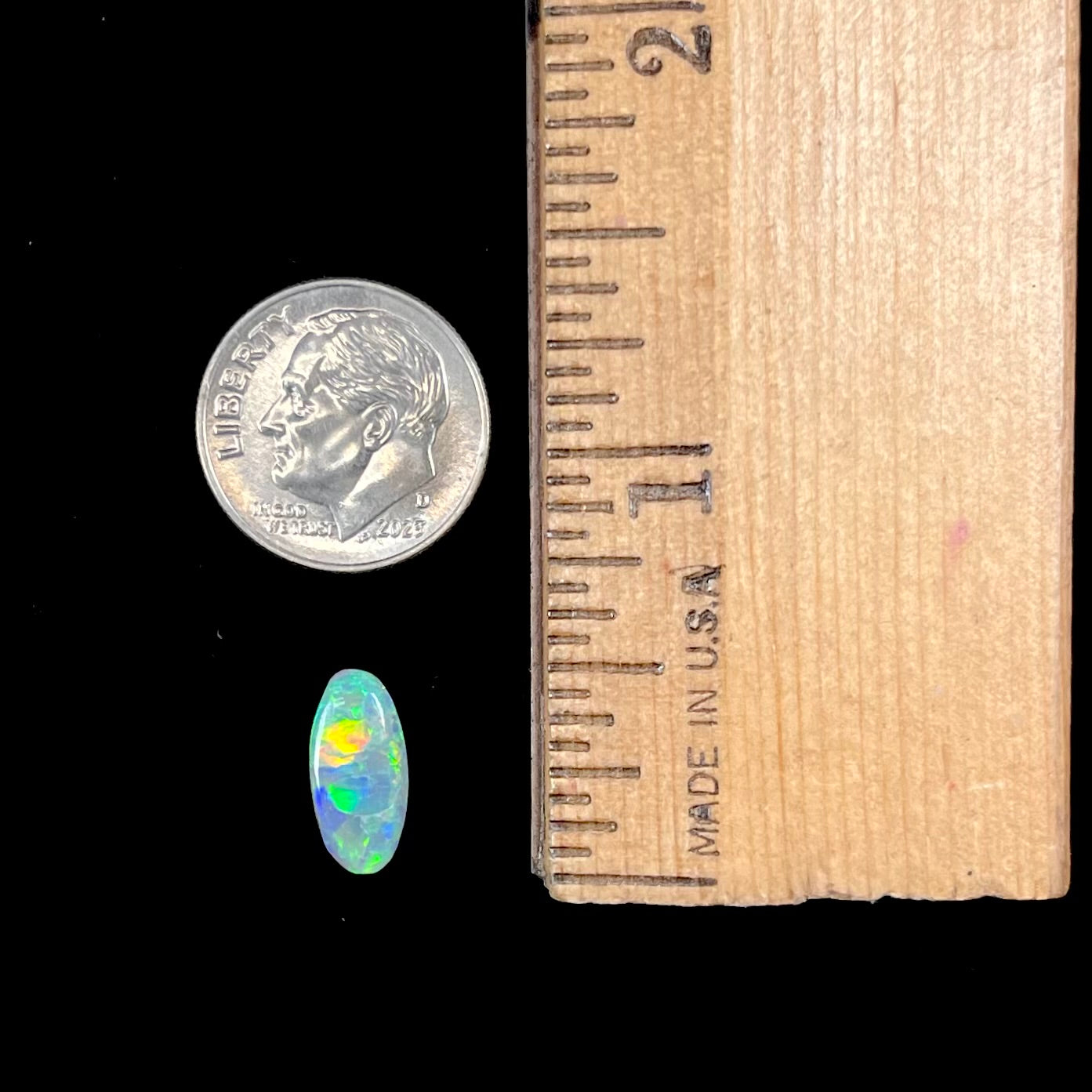 A loose, oval cabochon cut semi-black opal from Lightning Ridge, Australia.  The opal plays green and orange colors.