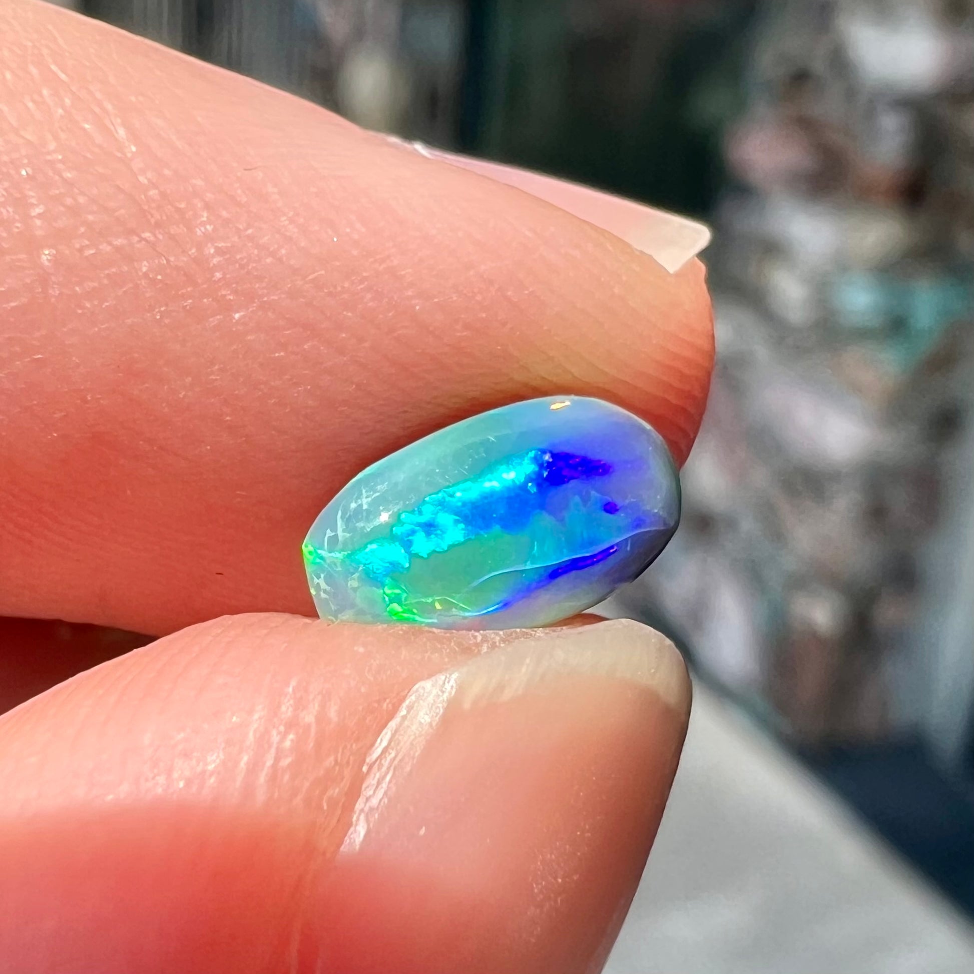 A loose, pill shaped black opal stone from Lightning Ridge, Australia.  The opal is green and blue.