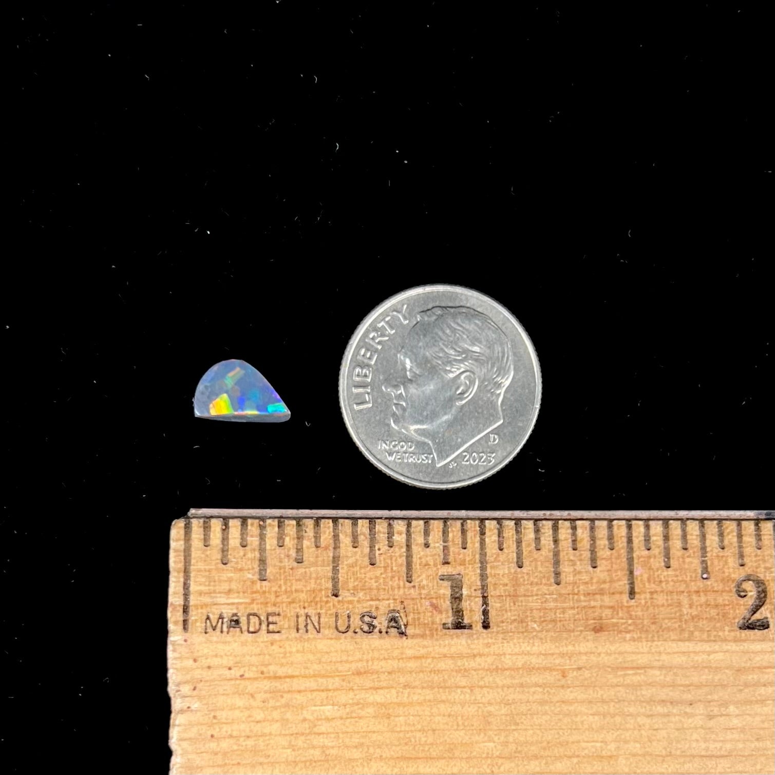 A loose, freeform cut black opal stone from Lightning Ridge, Australia.  The opal shines bright orange colors.