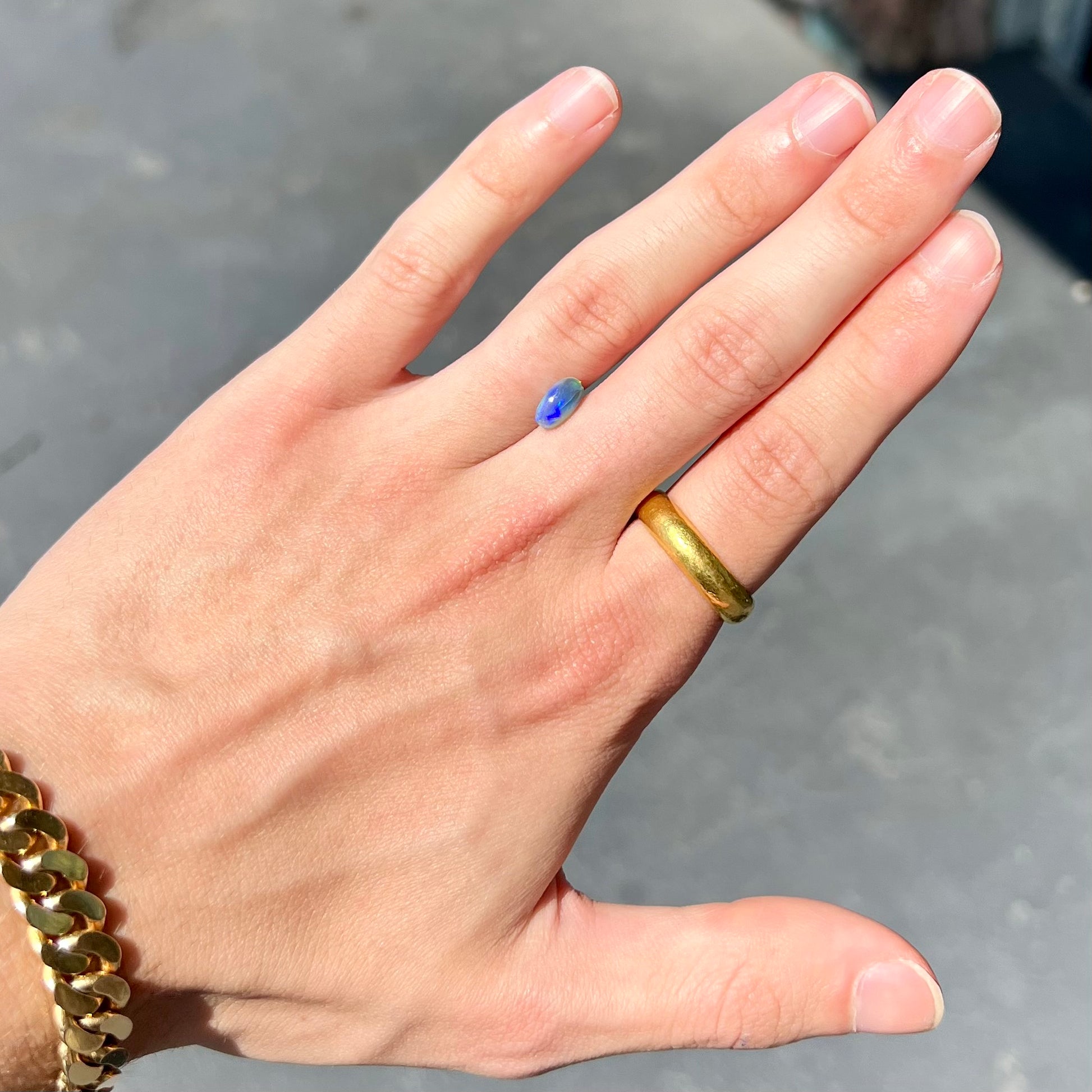 A loose, pill shaped black opal stone from Lightning Ridge, Australia.  The opal is green and blue.