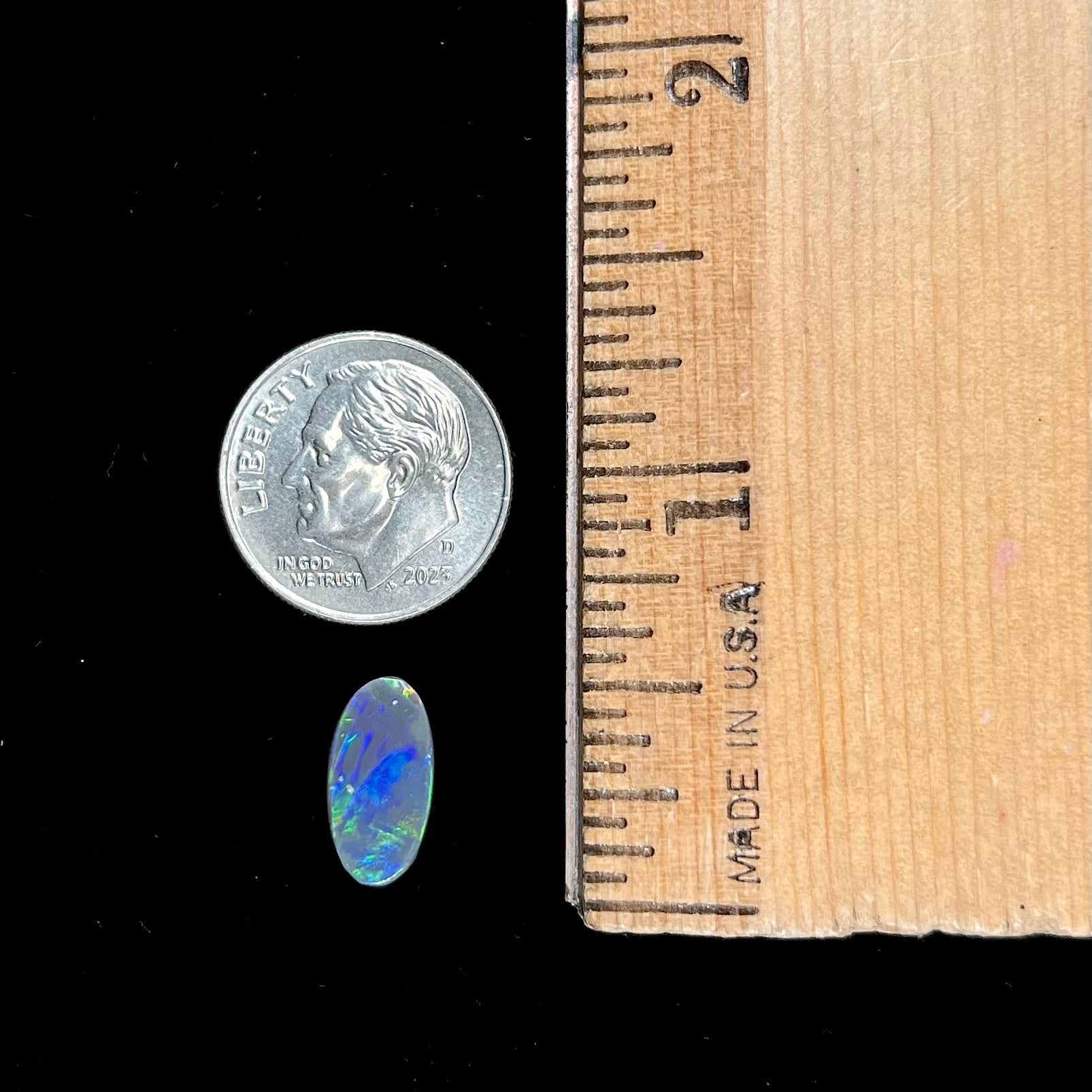 A loose, oval shaped black opal stone from Lightning Ridge, Australia.  The opal plays bright green and blue colors.
