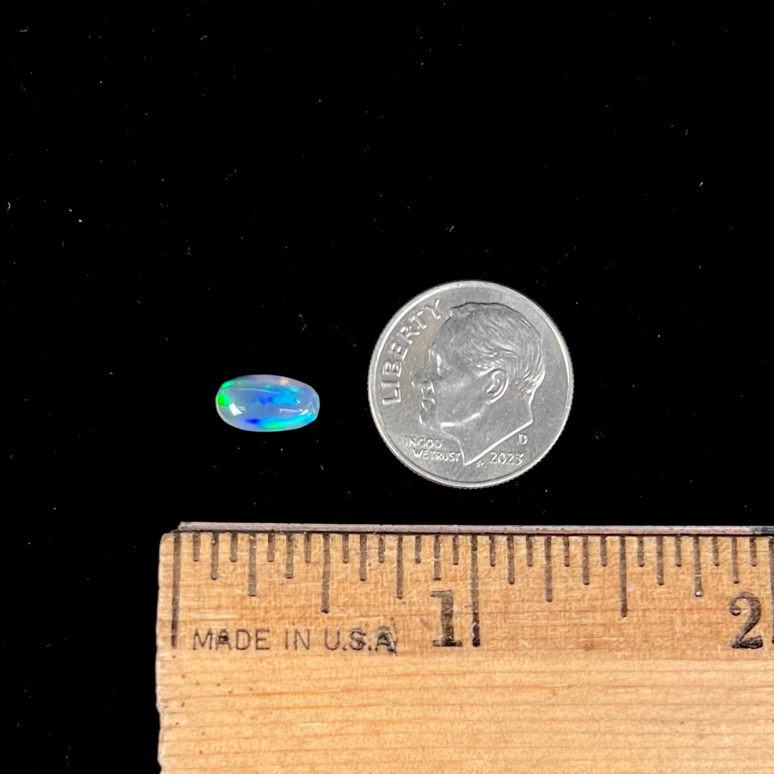 A loose, pill shaped black opal stone from Lightning Ridge, Australia.  The opal is green and blue.