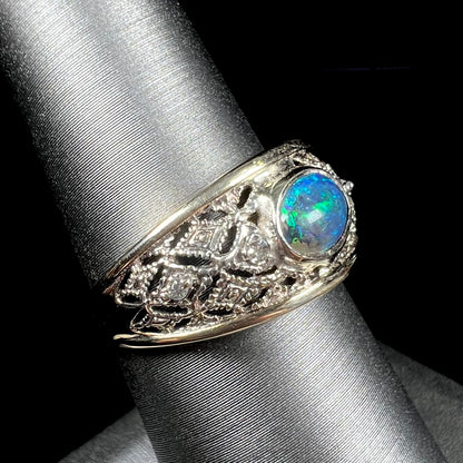 A ladies' yellow gold filigree style ring set with a natural black opal and diamond accents.