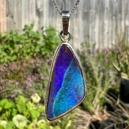 A sterling silver necklace set with a triangle shaped natural black boulder opal.