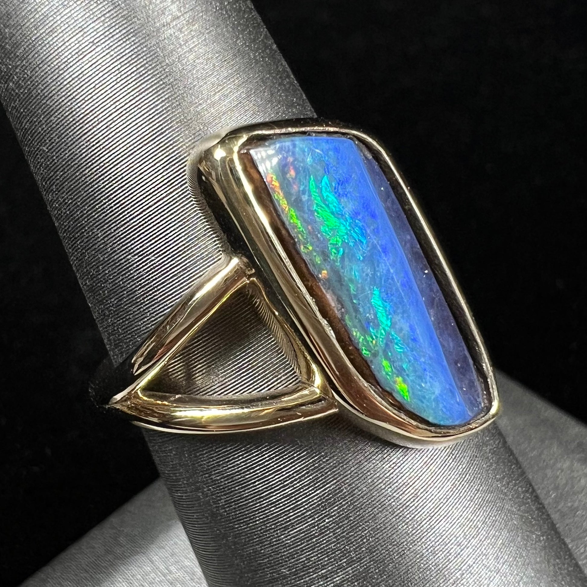 A ladies' split shank gold ring bezel set with a natural, Australian black boulder opal.