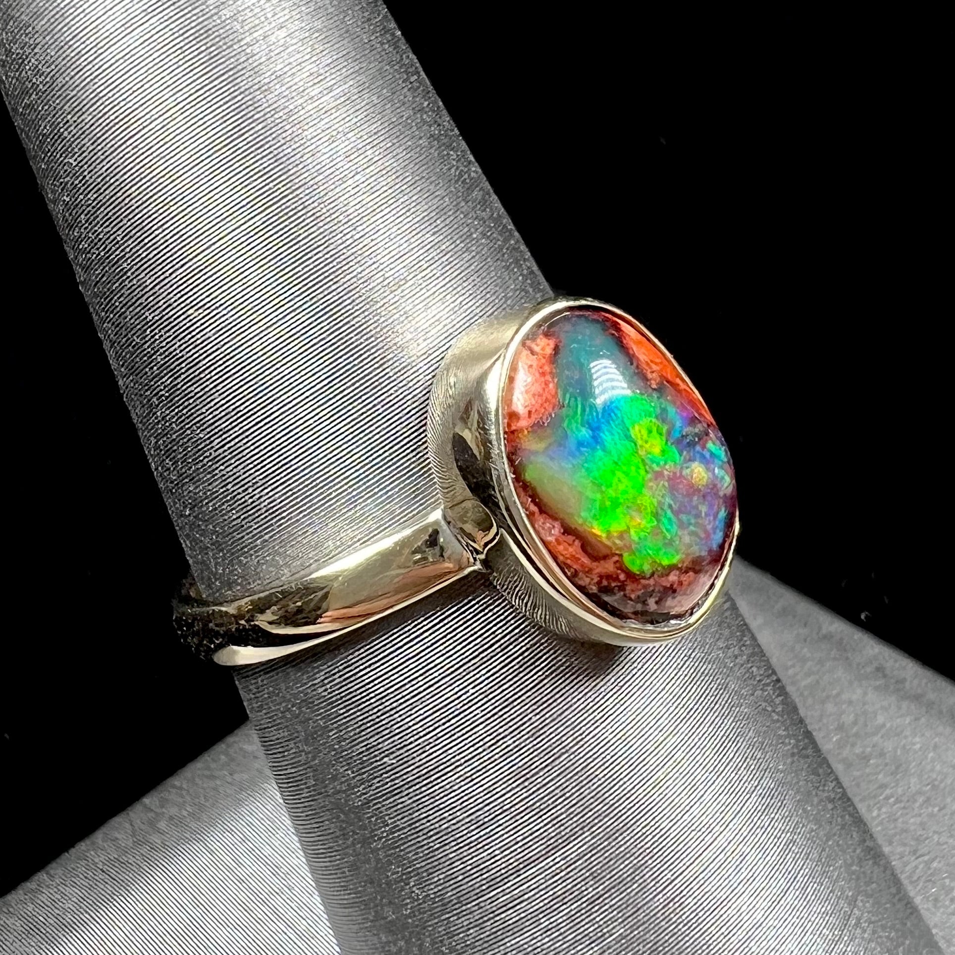 A ladies' yellow gold solitaire ring bezel set with an oval cabochon cut natural black Mexican cantera fire opal stone.