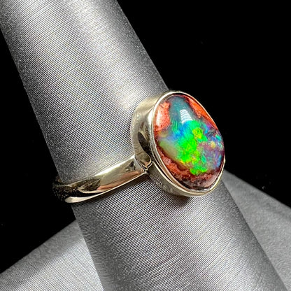 A ladies' yellow gold solitaire ring bezel set with an oval cabochon cut natural black Mexican cantera fire opal stone.