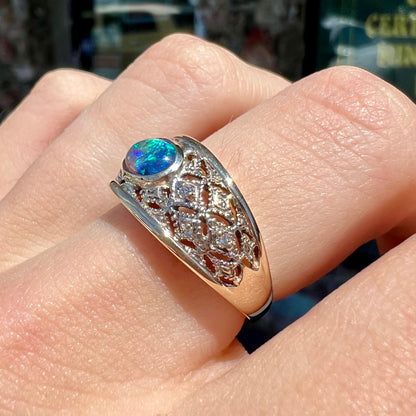 A ladies' yellow gold filigree style ring set with a natural black opal and diamond accents.