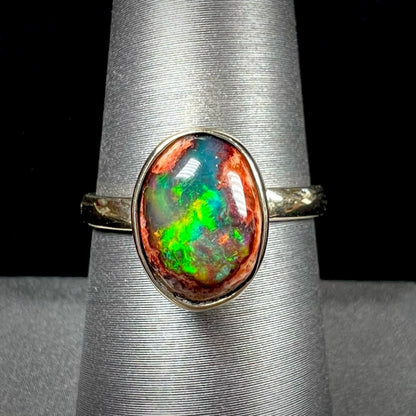 A ladies' yellow gold solitaire ring bezel set with an oval cabochon cut natural black Mexican cantera fire opal stone.