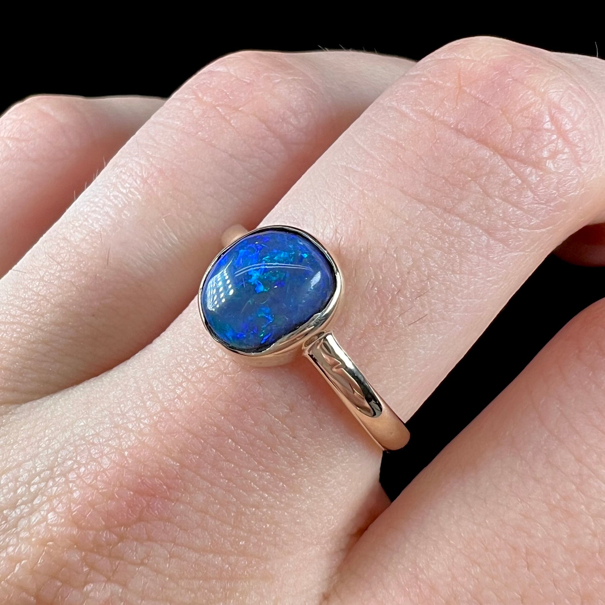 A ladies' natural black crystal opal solitaire ring handmade in 14 karat yellow gold.