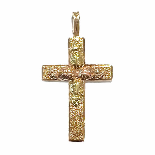 A cross made from yellow and rose gold Black Hills gold.  The cross features a leaf design.