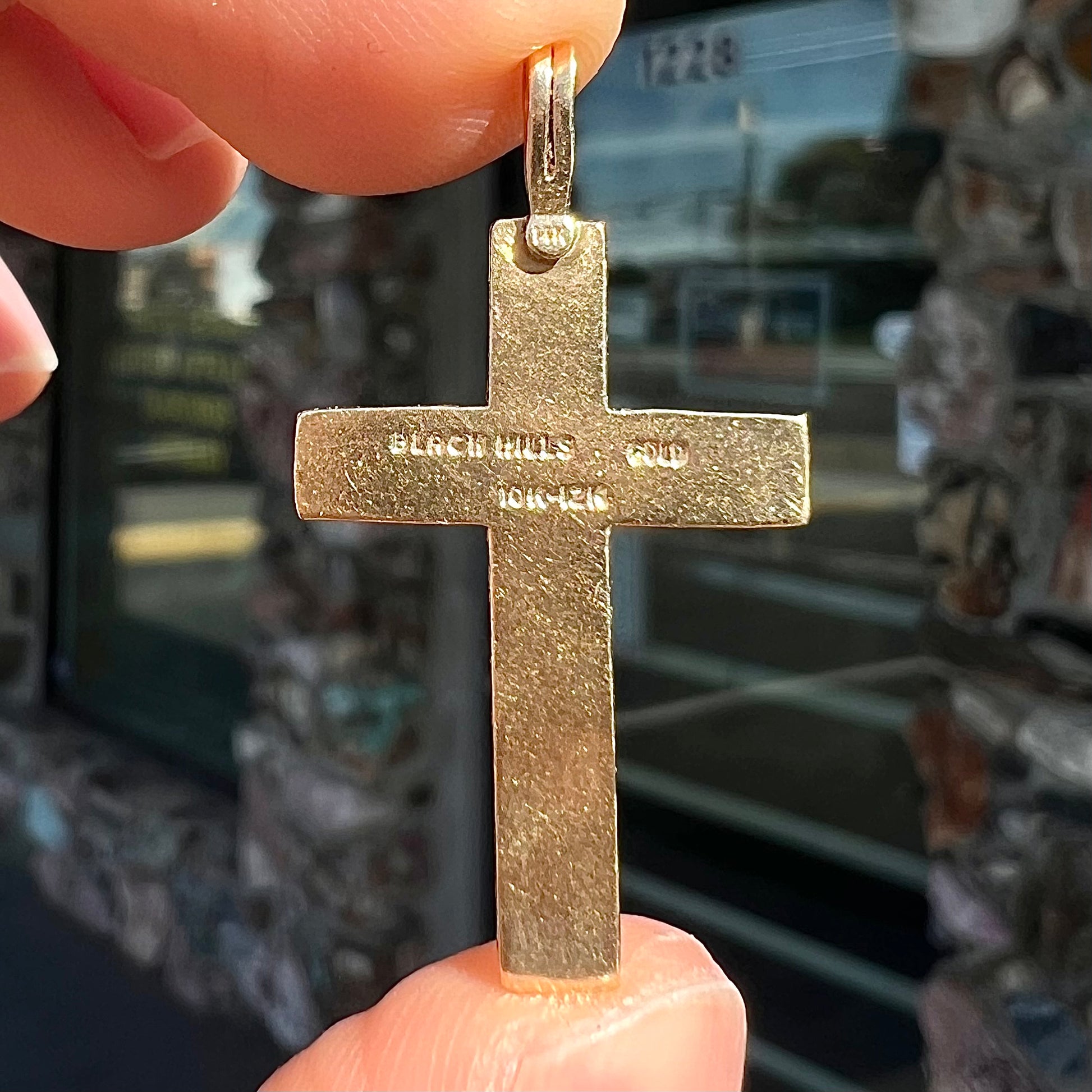 A cross made from yellow and rose gold Black Hills gold.  The cross features a leaf design.