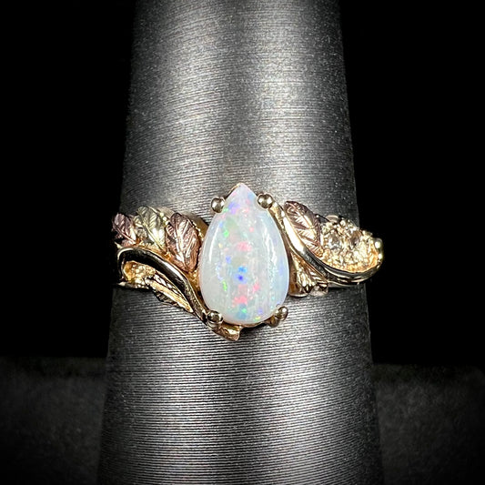 A ladies' two-tone yellow and rose Black Hills gold opal and diamond ring.  The opal is a pear shaped cabochon.