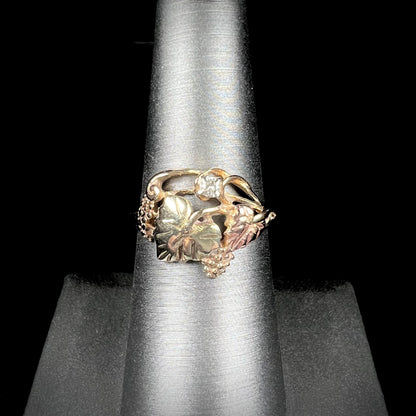 A ladies' two tone rose and yellow gold Black Hills gold diamond ring.  The ring exhibits a leaf design.