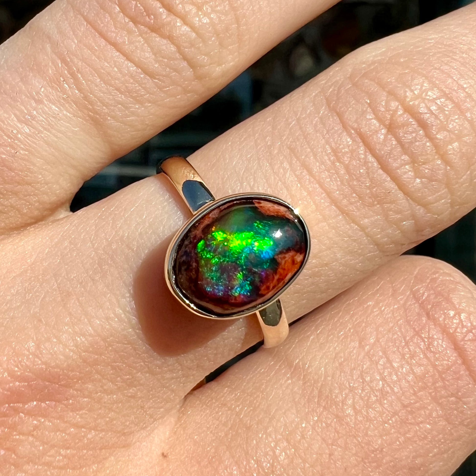 A ladies' yellow gold solitaire ring bezel set with an oval cabochon cut natural black Mexican cantera fire opal stone.