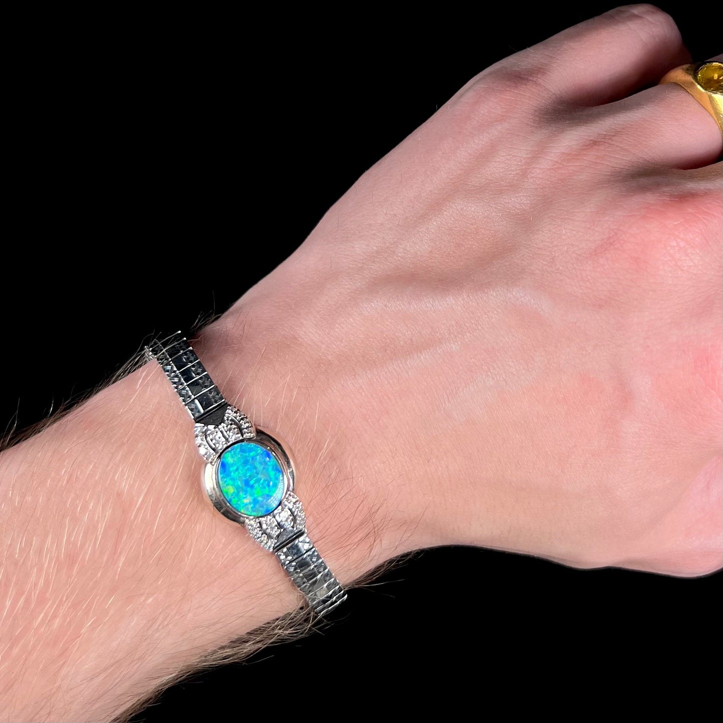 A ladies' art deco style white gold and stainless steel bracelet set with a natural black opal doublet and diamonds.