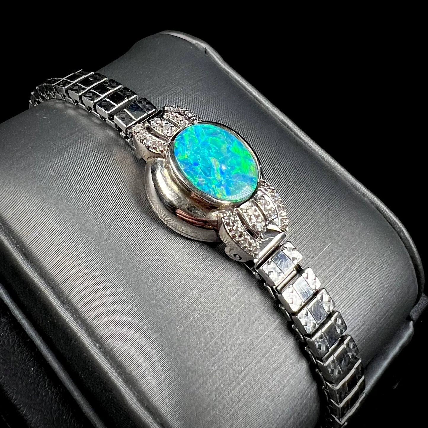 A ladies' art deco style white gold and stainless steel bracelet set with a natural black opal doublet and diamonds.