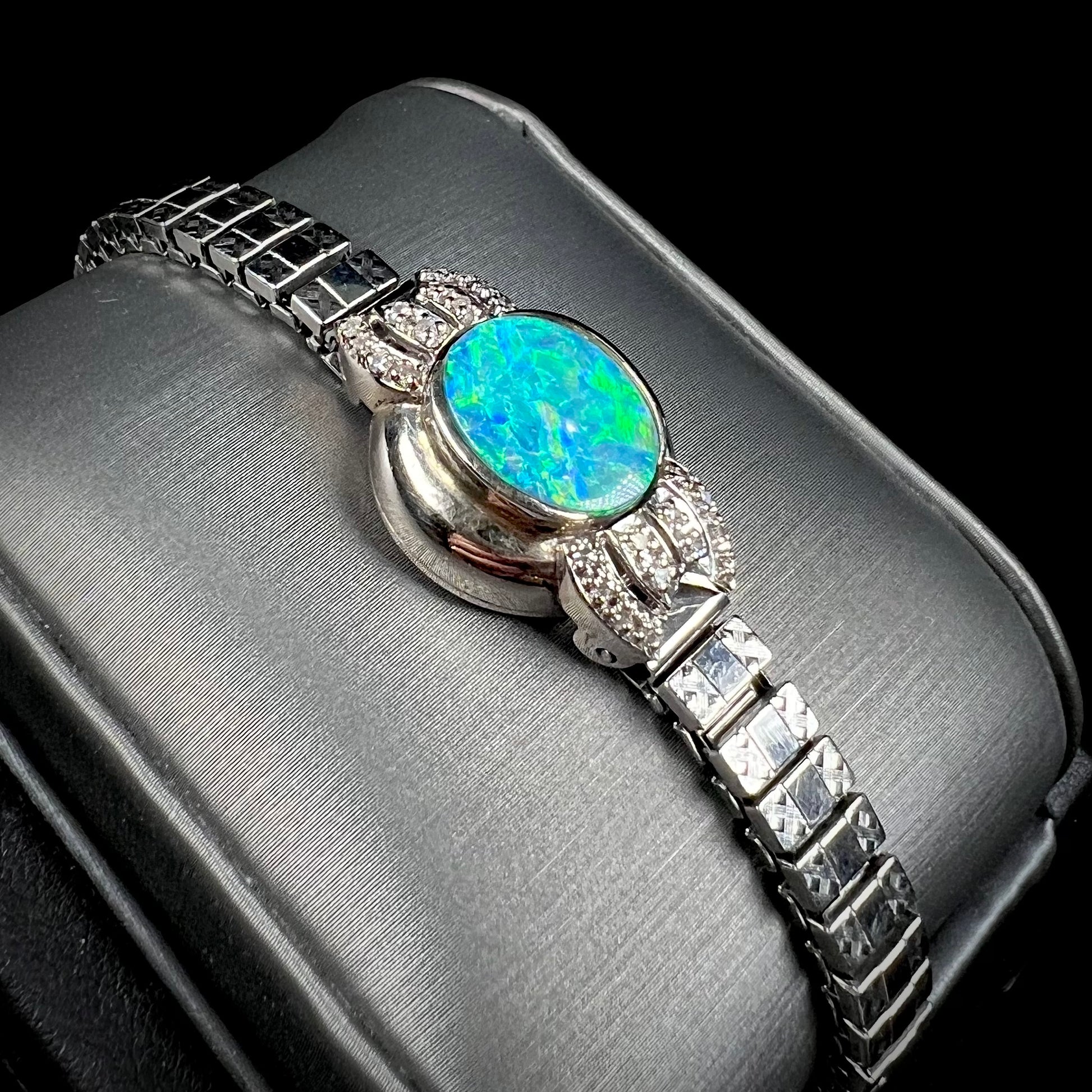 A ladies' art deco style white gold and stainless steel bracelet set with a natural black opal doublet and diamonds.