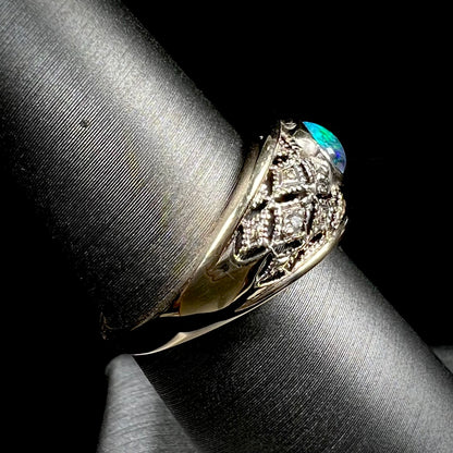 A ladies' yellow gold filigree style ring set with a natural black opal and diamond accents.