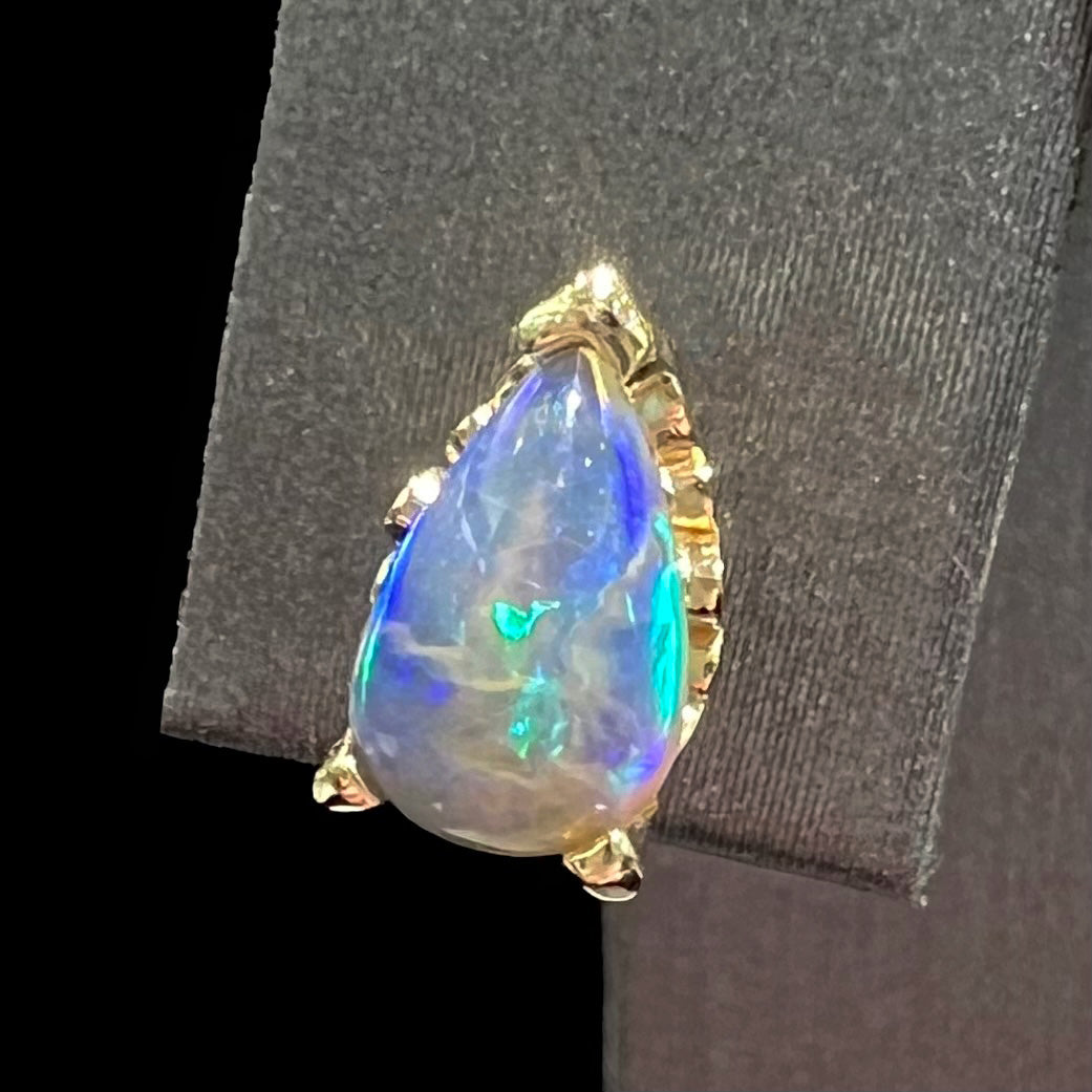 A pair of pear shaped natural black opal stud earrings in filigree style yellow gold baskets.