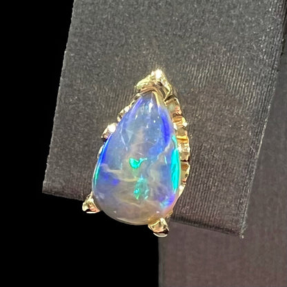 A pair of pear shaped natural black opal stud earrings in filigree style yellow gold baskets.