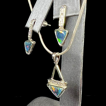 A white gold pendant and earrings set mounted with triangle cut natural black opals and diamonds.