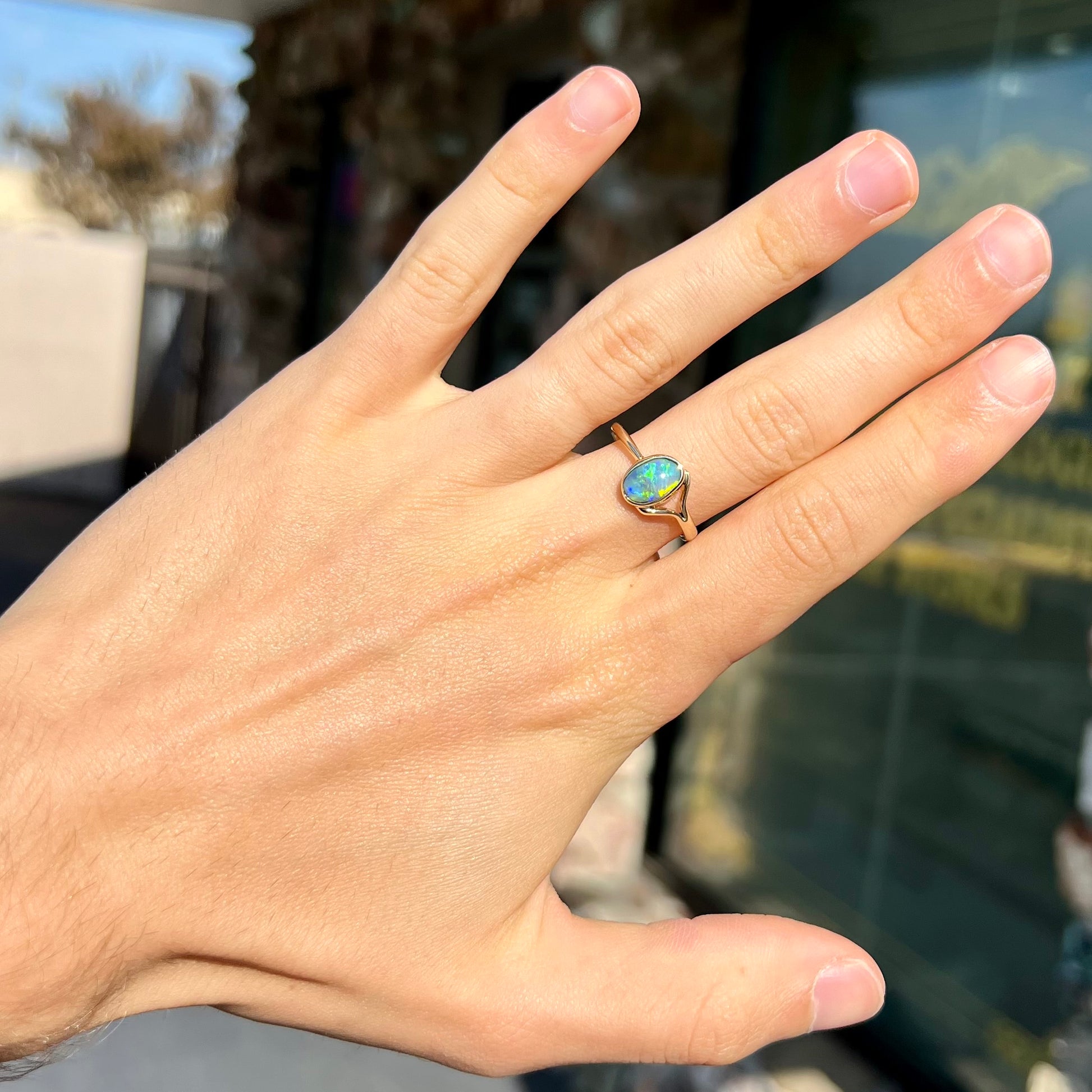 A ladies' oval cut black crystal opal solitaire ring handmade with a single split shank in yellow gold.