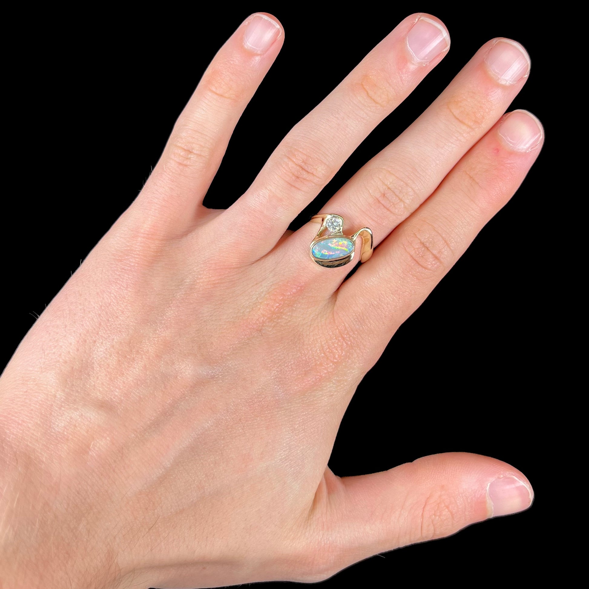A ladies' yellow gold, bezel set ring mounted with a natural 1.15 carat black opal and round diamond.