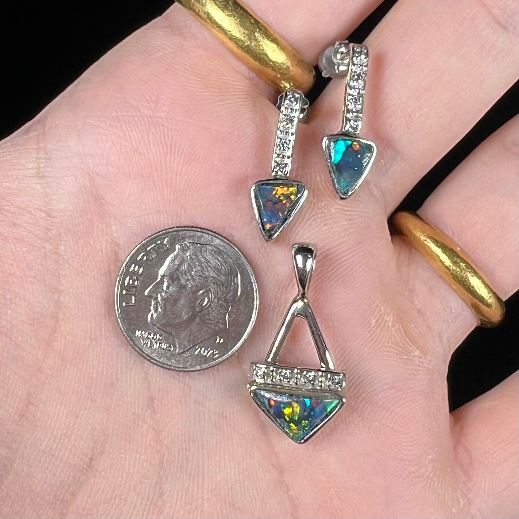 A white gold pendant and earrings set mounted with triangle cut natural black opals and diamonds.