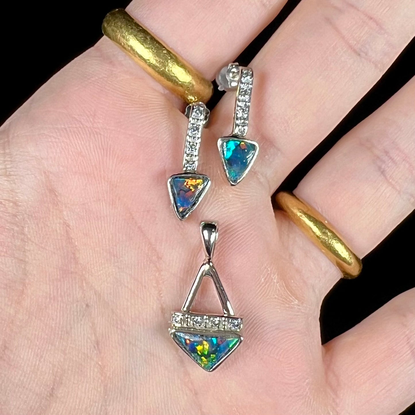 A white gold pendant and earrings set mounted with triangle cut natural black opals and diamonds.