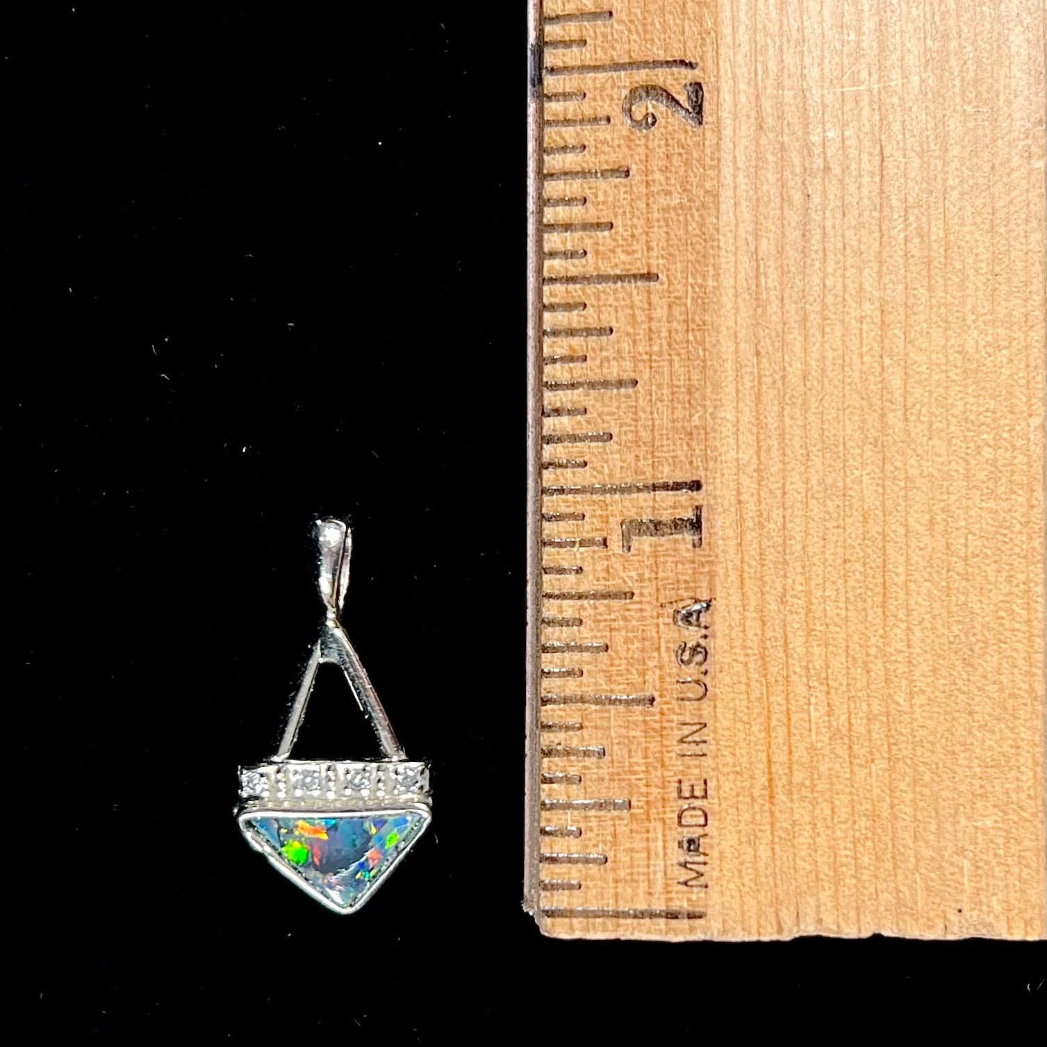 A white gold pendant and earrings set mounted with triangle cut natural black opals and diamonds.
