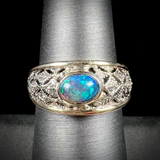 A ladies' yellow gold filigree style ring set with a natural black opal and diamond accents.