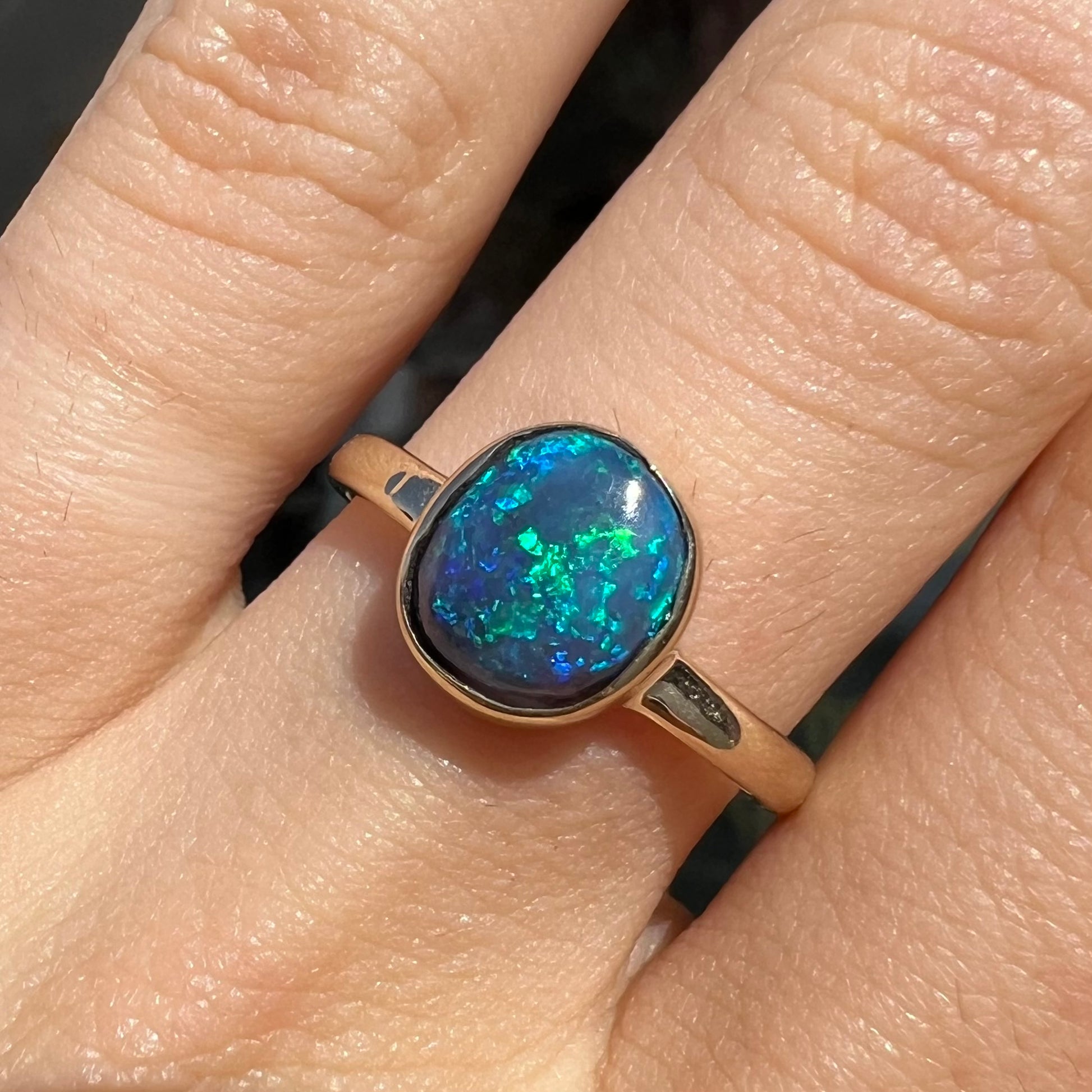 A ladies' natural black crystal opal solitaire ring handmade in 14 karat yellow gold.