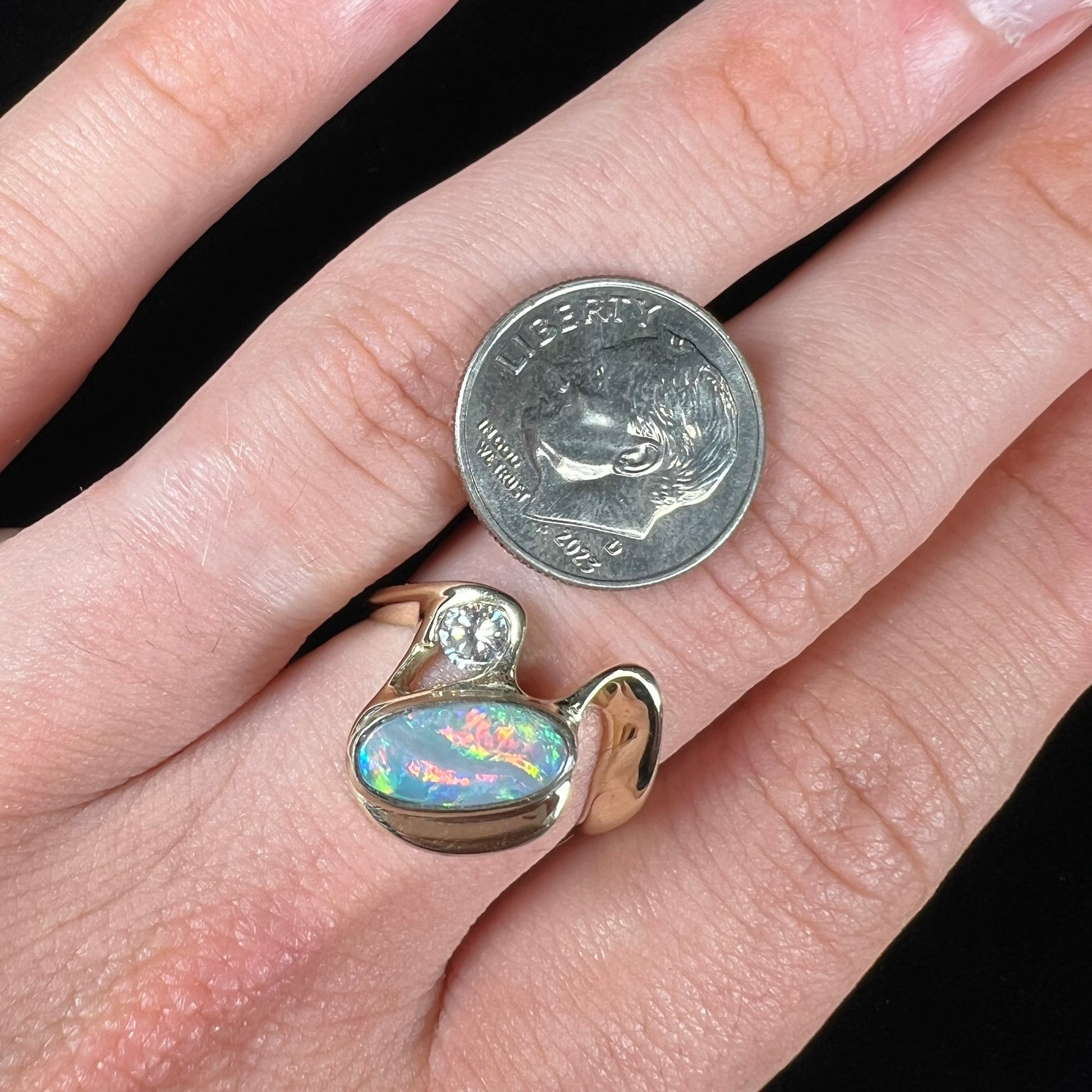 A ladies' yellow gold, bezel set ring mounted with a natural 1.15 carat black opal and round diamond.