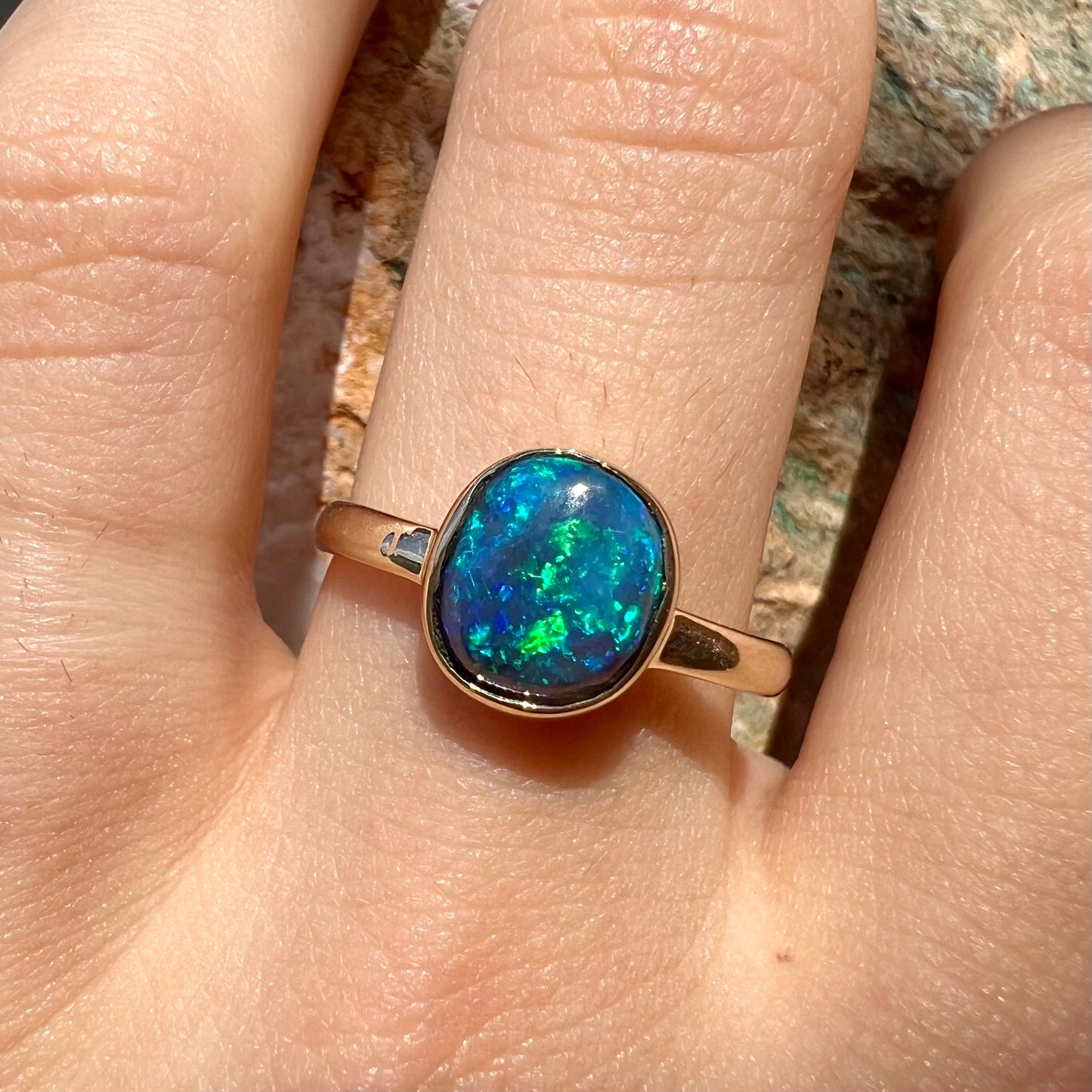 A ladies' natural black crystal opal solitaire ring handmade in 14 karat yellow gold.