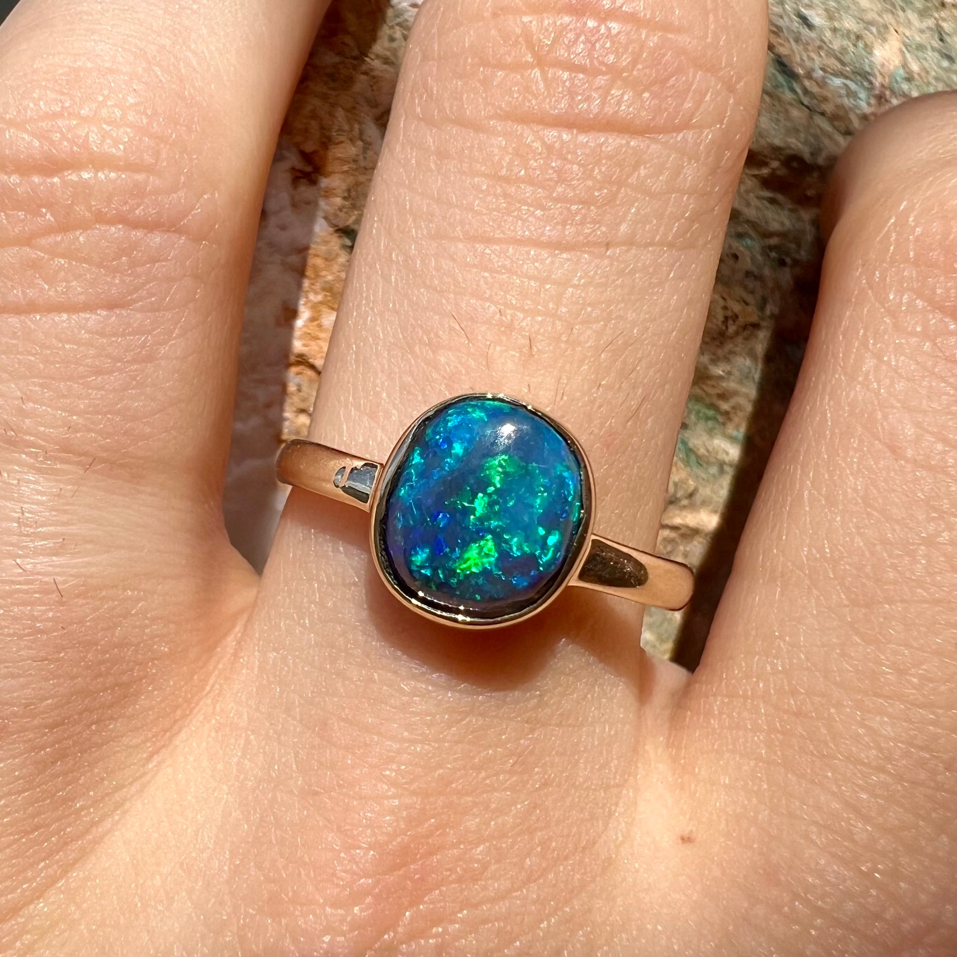 A ladies' natural black crystal opal solitaire ring handmade in 14 karat yellow gold.
