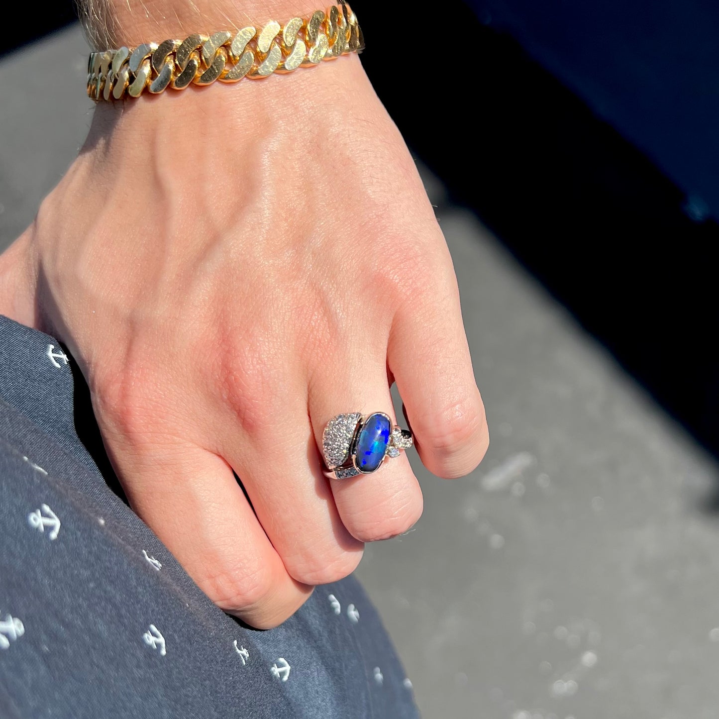 A platinum ring set with an oval cut black opal and round cut diamonds in a leaf design.