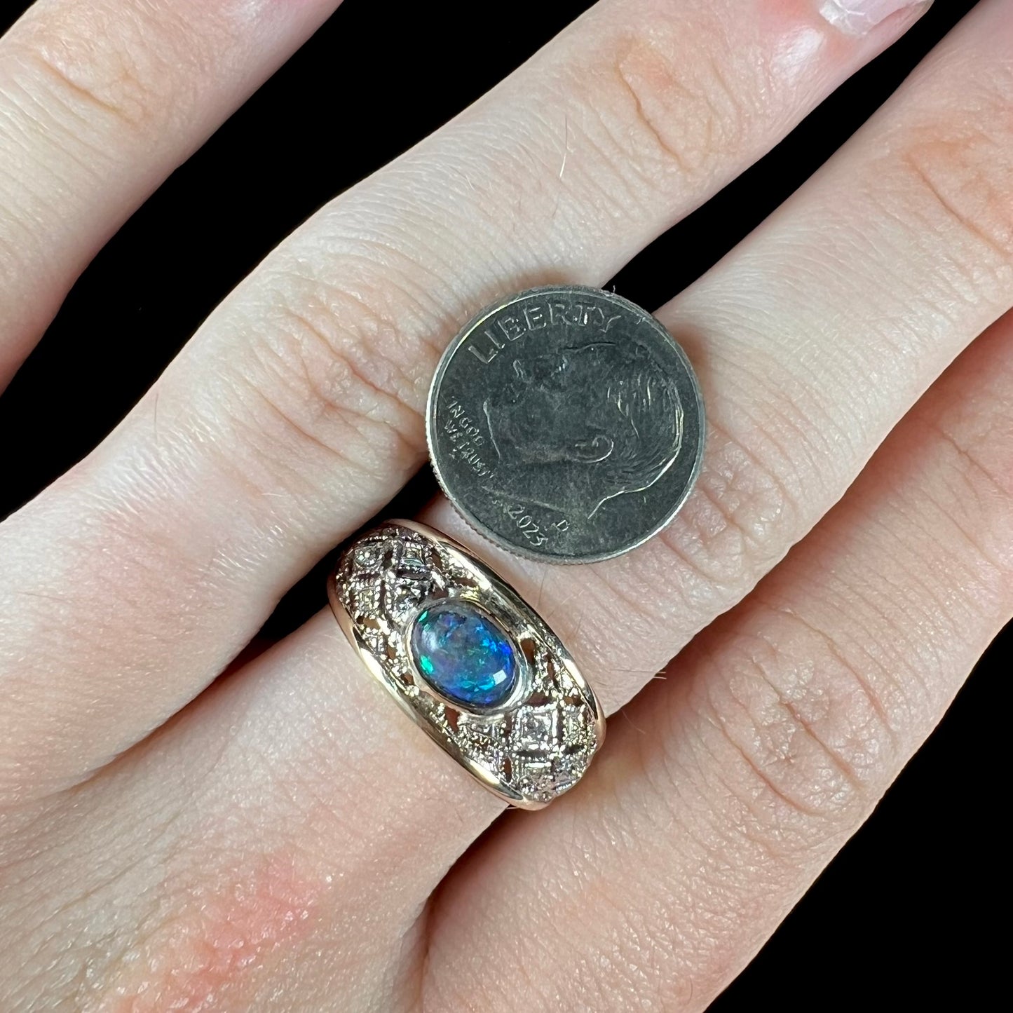 A ladies' yellow gold filigree style ring set with a natural black opal and diamond accents.