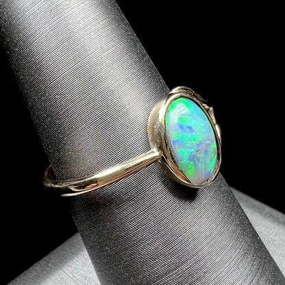 A ladies' oval cut black crystal opal solitaire ring handmade with a single split shank in yellow gold.
