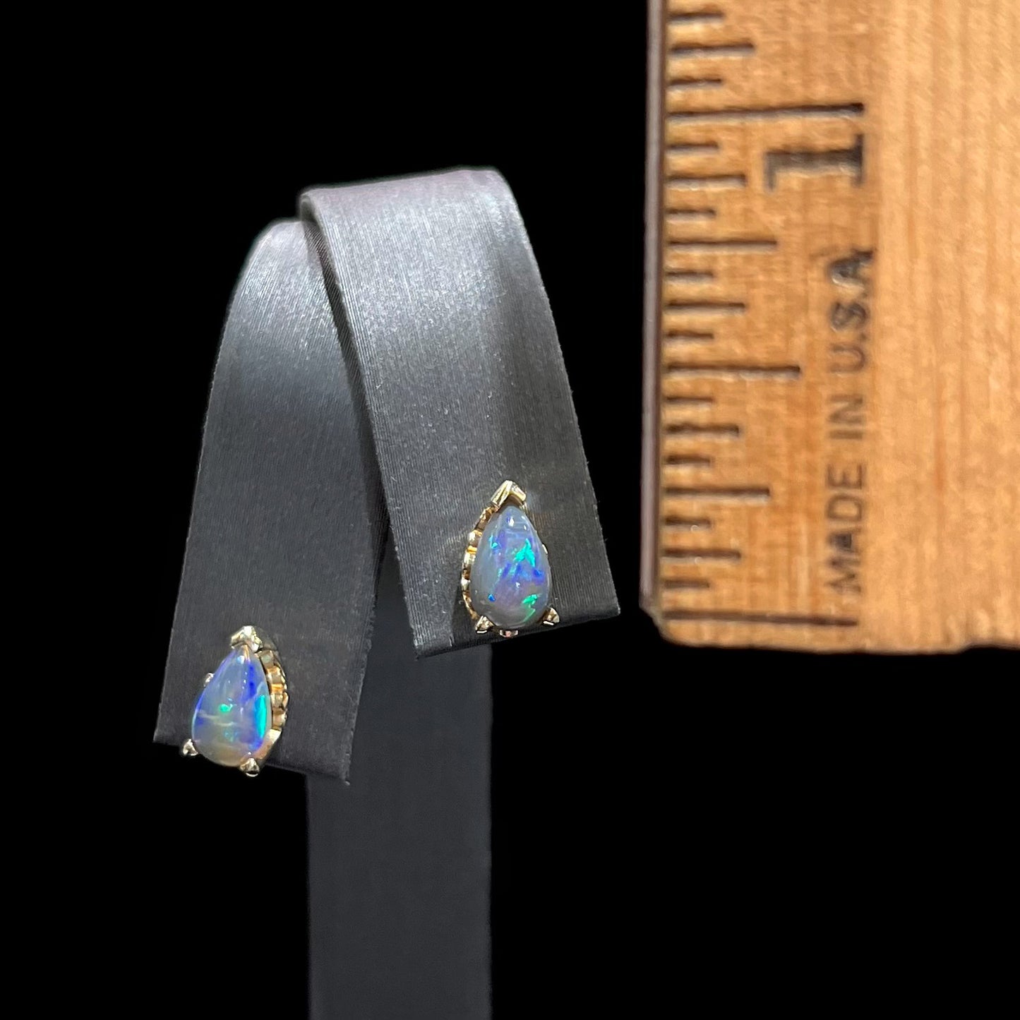 A pair of pear shaped natural black opal stud earrings in filigree style yellow gold baskets.